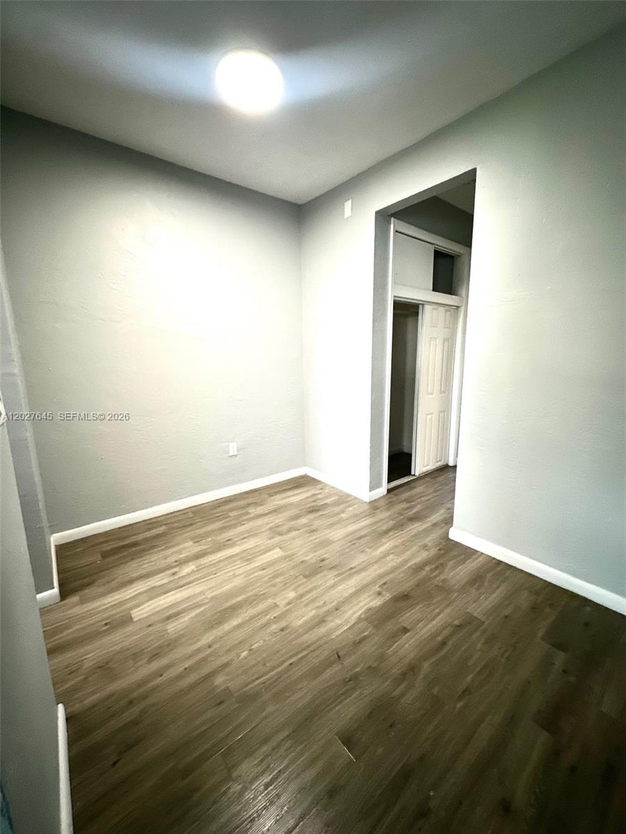 An empty room features light gray walls, wood-look flooring, and an open doorway to a closet — 710 Meridian Ave # 9, Miami Beach FL 33139, MIAMI BEACH, FL