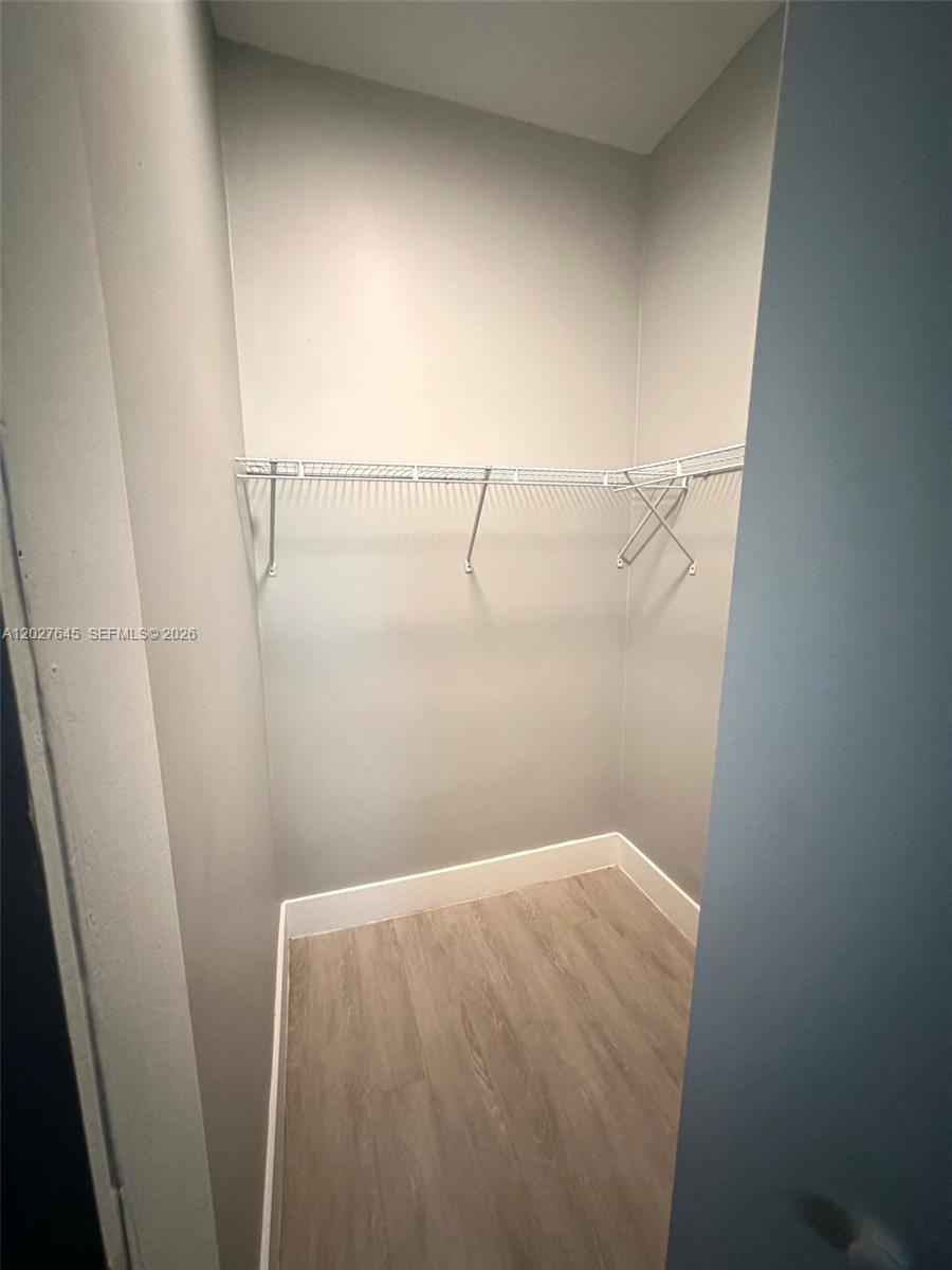 A small walk-in closet features light gray walls, wood-look flooring, and white wire shelving — 710 Meridian Ave # 9, Miami Beach FL 33139, MIAMI BEACH, FL