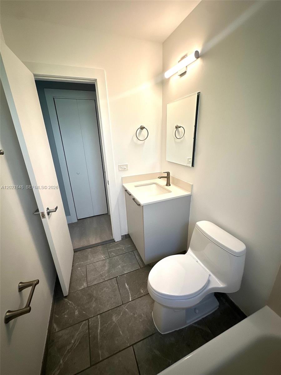 A small bathroom features a vanity with a sink, a toilet, and gray tile flooring — 710 Meridian Ave # 9, Miami Beach FL 33139, MIAMI BEACH, FL