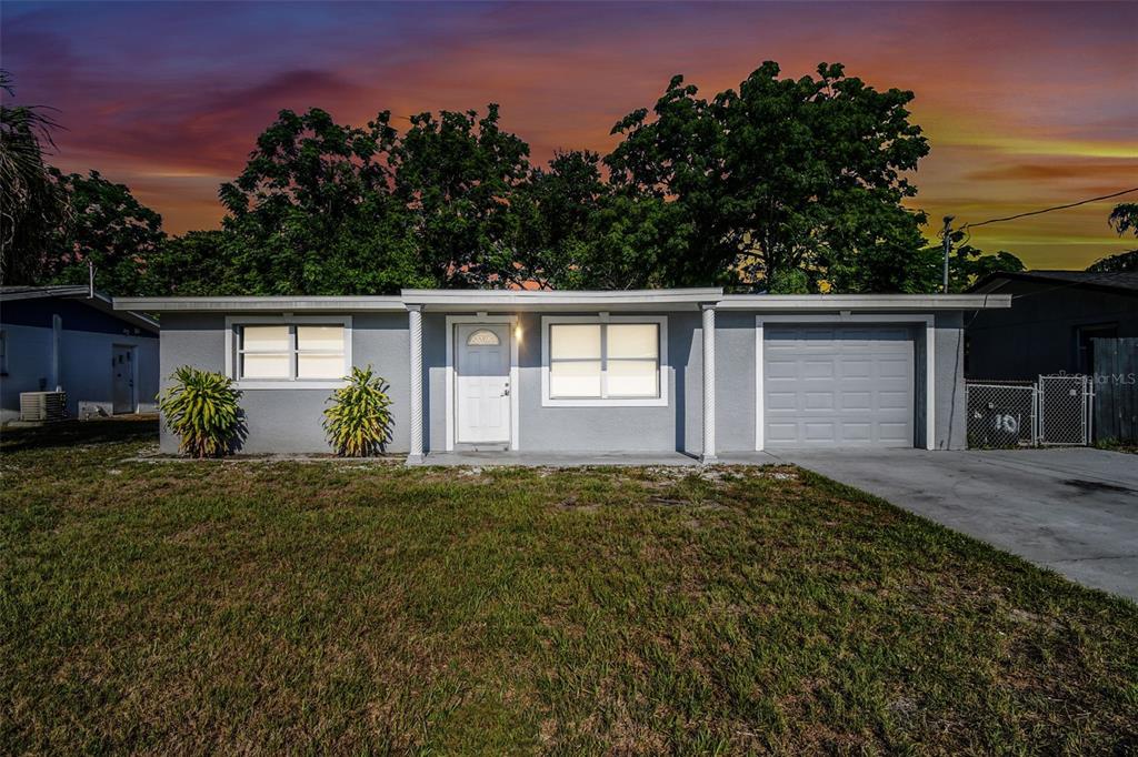A single-story gray house with a white front door, two windows, and an attached garage — 11011 PICKERING LANE, PORT RICHEY, FL