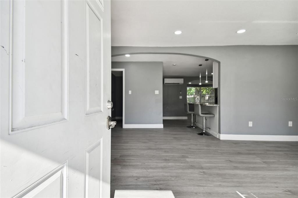 A view through an open white door into a living area with gray flooring — 11011 PICKERING LANE, PORT RICHEY, FL