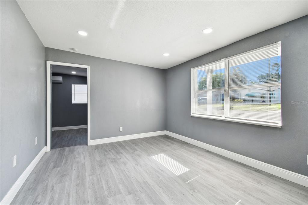 A room with gray walls, light wood-look flooring, recessed lighting, and a large window — 11011 PICKERING LANE, PORT RICHEY, FL