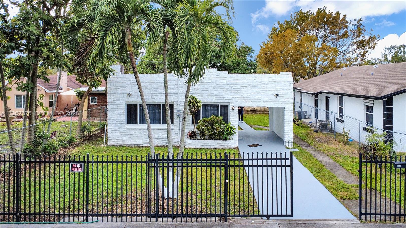A white, stone-textured single-story house features a front carport and a black metal fence — 7770 NW 9th Ave, Miami FL 33150, MIAMI, FL