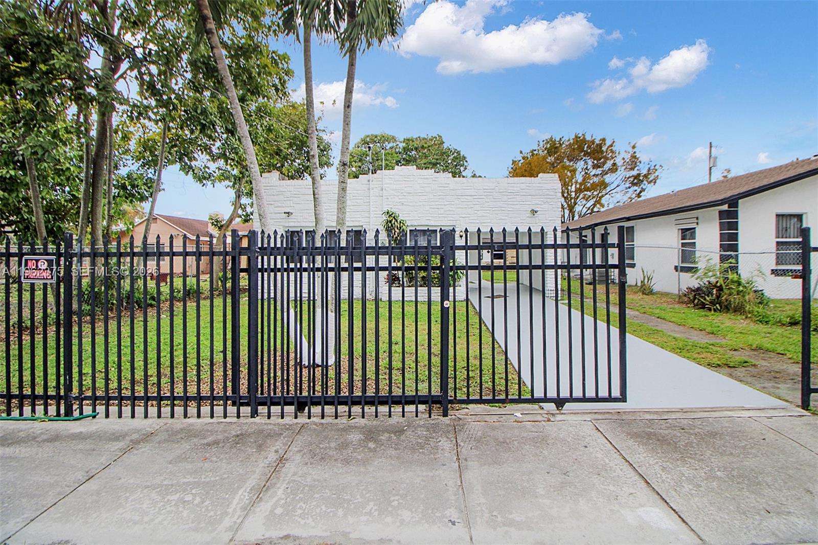 A white, single-story house with a flat roof sits behind a black metal fence — 7770 NW 9th Ave, Miami FL 33150, MIAMI, FL