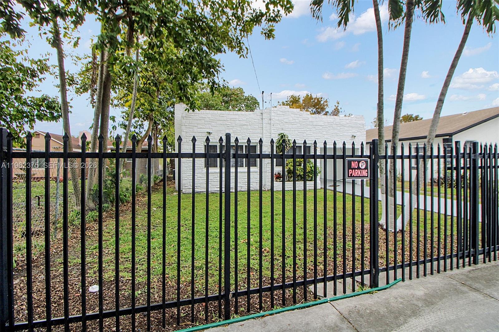 A white stone house sits behind a black metal fence with a no parking sign — 7770 NW 9th Ave, Miami FL 33150, MIAMI, FL