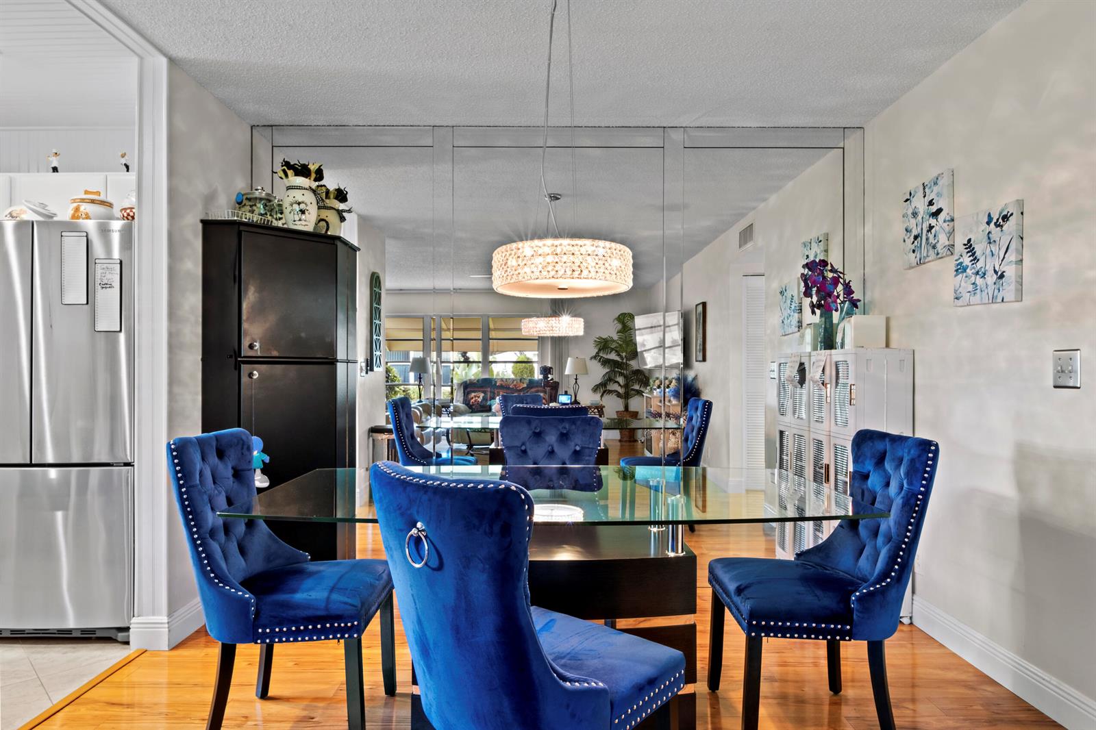 A dining room features a glass table, blue tufted chairs, and a large mirrored wall — 5078 Lakefront Boulevard # D, Delray Beach FL 33484, DELRAY BEACH, FL