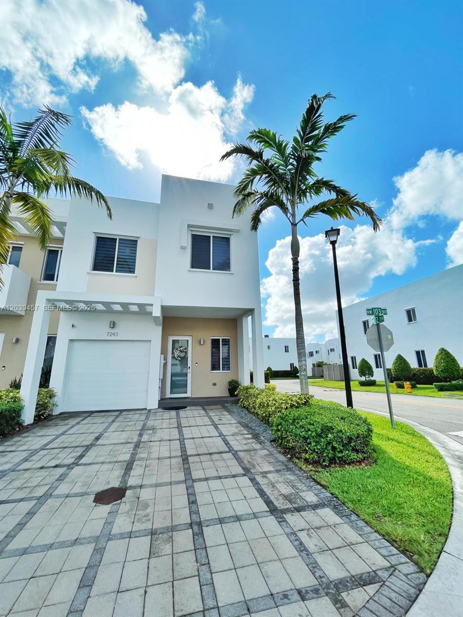 A two-story white townhouse features a paved driveway, a single-car garage, and a palm tree — 7243 NW 103rd Path, Doral FL 33178, DORAL, FL