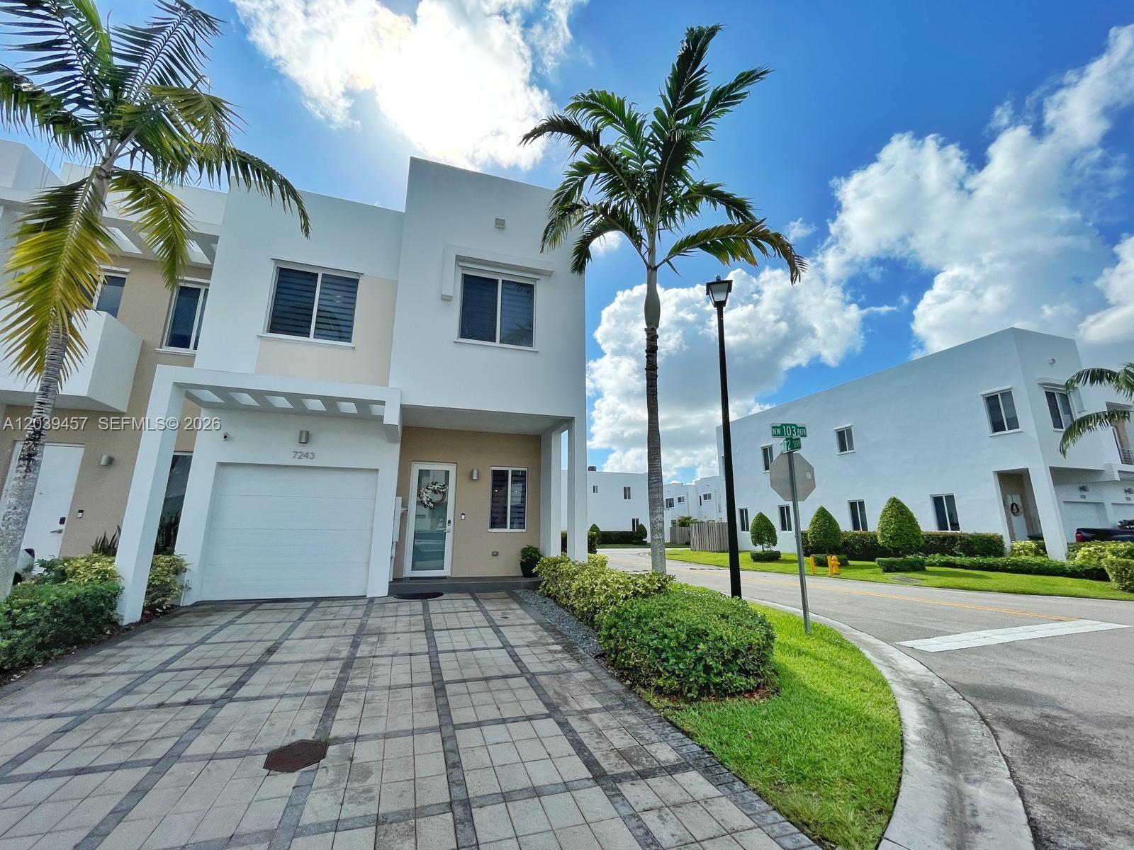 A two-story white townhouse features a paved driveway, a garage, and a palm tree — 7243 NW 103rd Path, Doral FL 33178, DORAL, FL