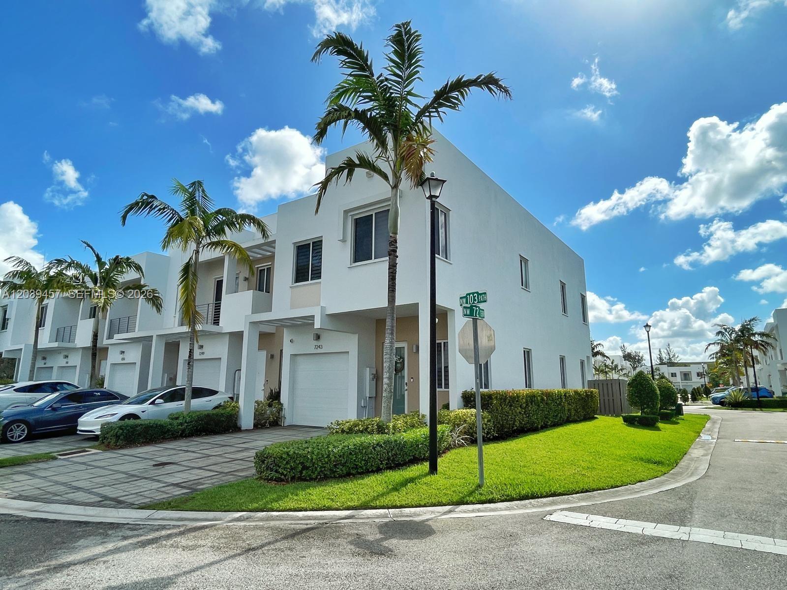A white two-story townhouse with a garage and palm trees sits on a corner lot — 7243 NW 103rd Path, Doral FL 33178, DORAL, FL