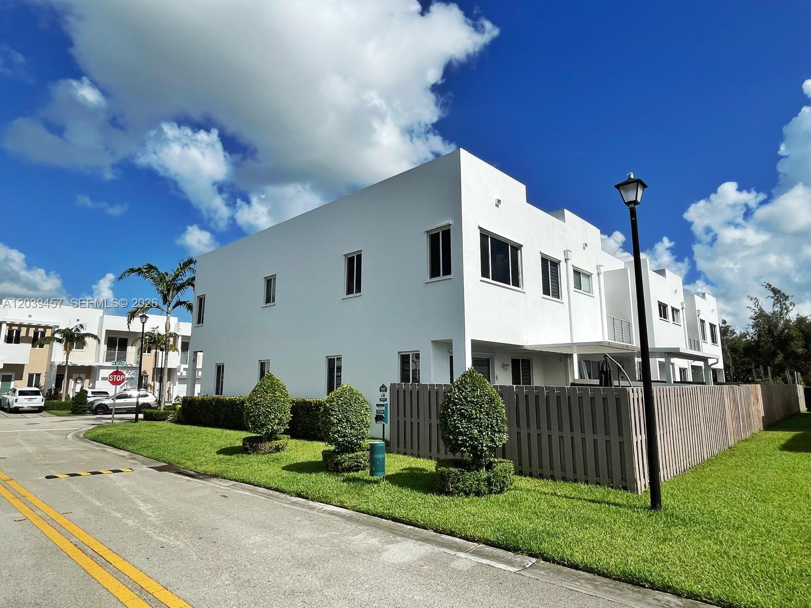 A white two-story townhouse with a fenced yard and a street lamp on a sunny day — 7243 NW 103rd Path, Doral FL 33178, DORAL, FL