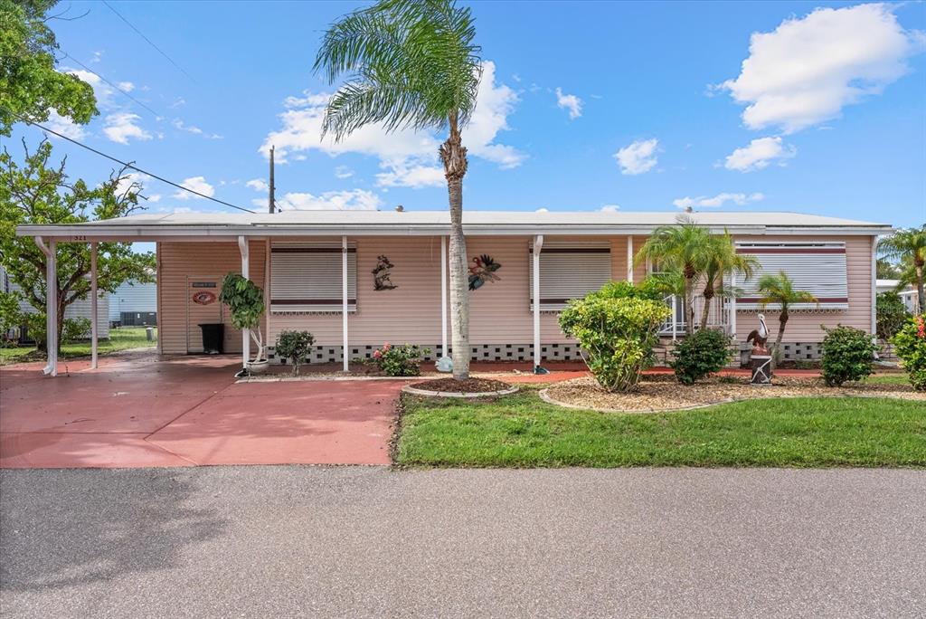 A single-story pink mobile home features a carport, palm tree, and landscaped front yard — 321 BLACKBURN BOULEVARD, NORTH PORT, FL