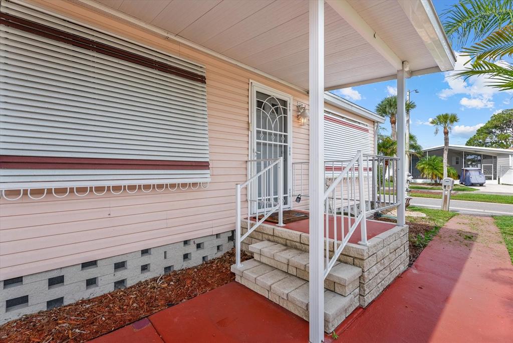 A pink mobile home exterior features a small front porch with white railings and steps — 321 BLACKBURN BOULEVARD, NORTH PORT, FL