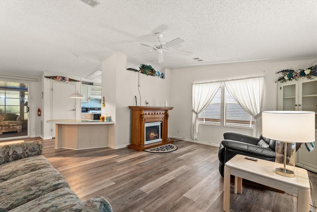 A living room features wood-look flooring, a fireplace, a ceiling fan, and an adjacent kitchen — 321 BLACKBURN BOULEVARD, NORTH PORT, FL