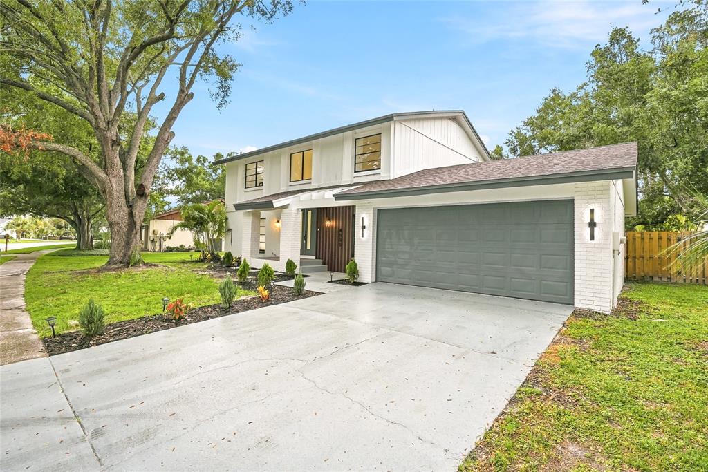 A two-story house with a white brick facade, gray garage door, and a concrete driveway — 4505 WHITWORTH LANE, TAMPA, FL