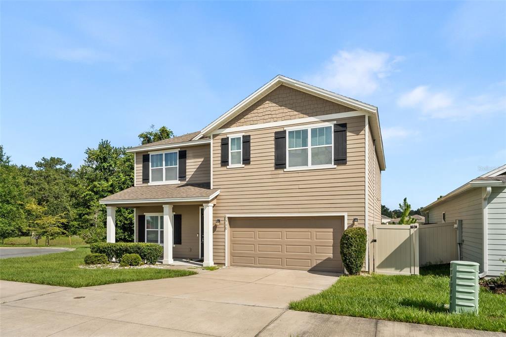 A two-story suburban house with tan siding, a front porch, and an attached two-car garage — 8008 SW 62ND COURT, GAINESVILLE, FL