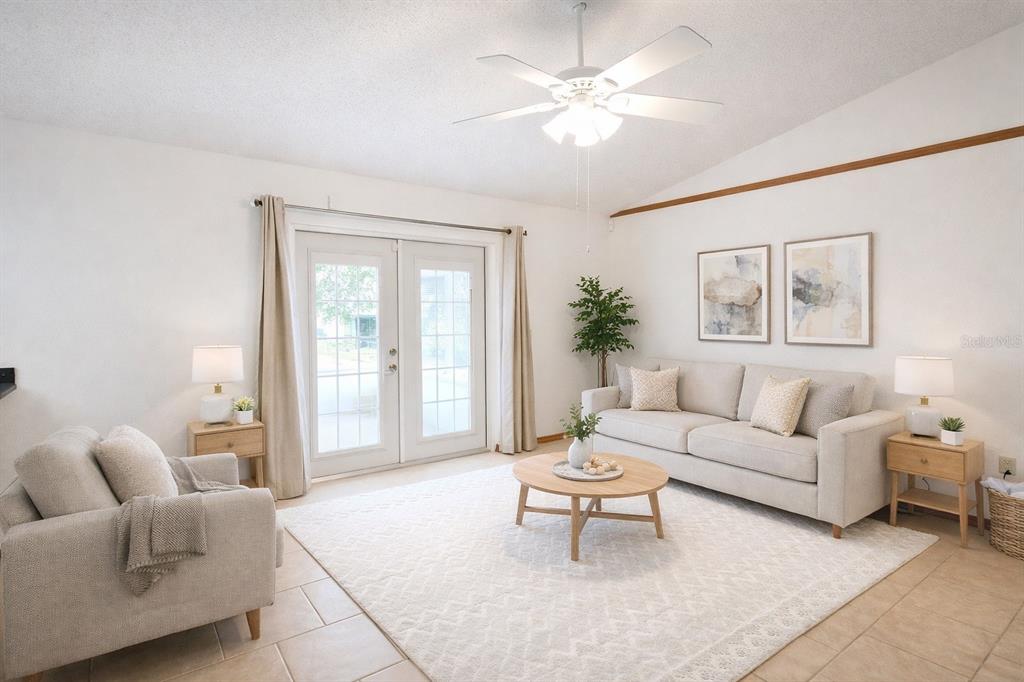 A living room features a sofa, armchair, coffee table, ceiling fan, and glass patio doors — 3924 CREWS LAKE DRIVE, LAKELAND, FL