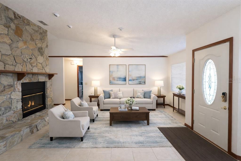A living room features a stone fireplace, a white sofa, two armchairs, and tile flooring — 3924 CREWS LAKE DRIVE, LAKELAND, FL