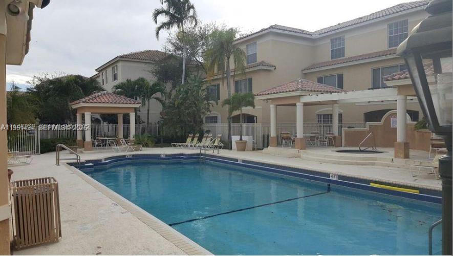 A swimming pool with a surrounding patio, lounge chairs, and covered seating areas near apartment buildings — 741 SW 148th Ave # 705, Sunrise FL 33325, SUNRISE, FL