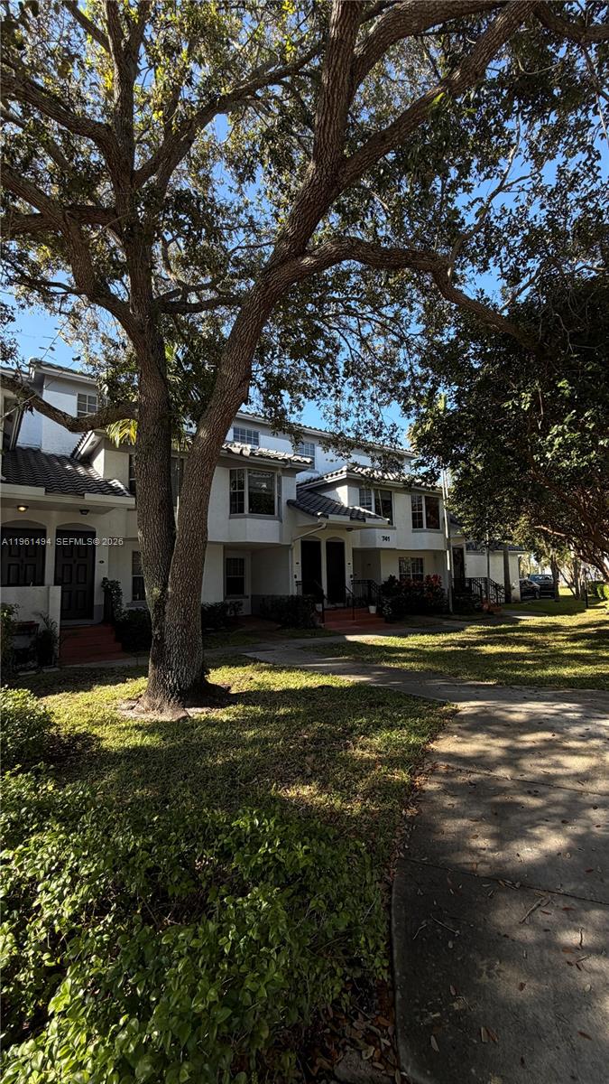 A multi-story residential building with white stucco walls and dark roofs sits behind large trees — 741 SW 148th Ave # 705, Sunrise FL 33325, SUNRISE, FL