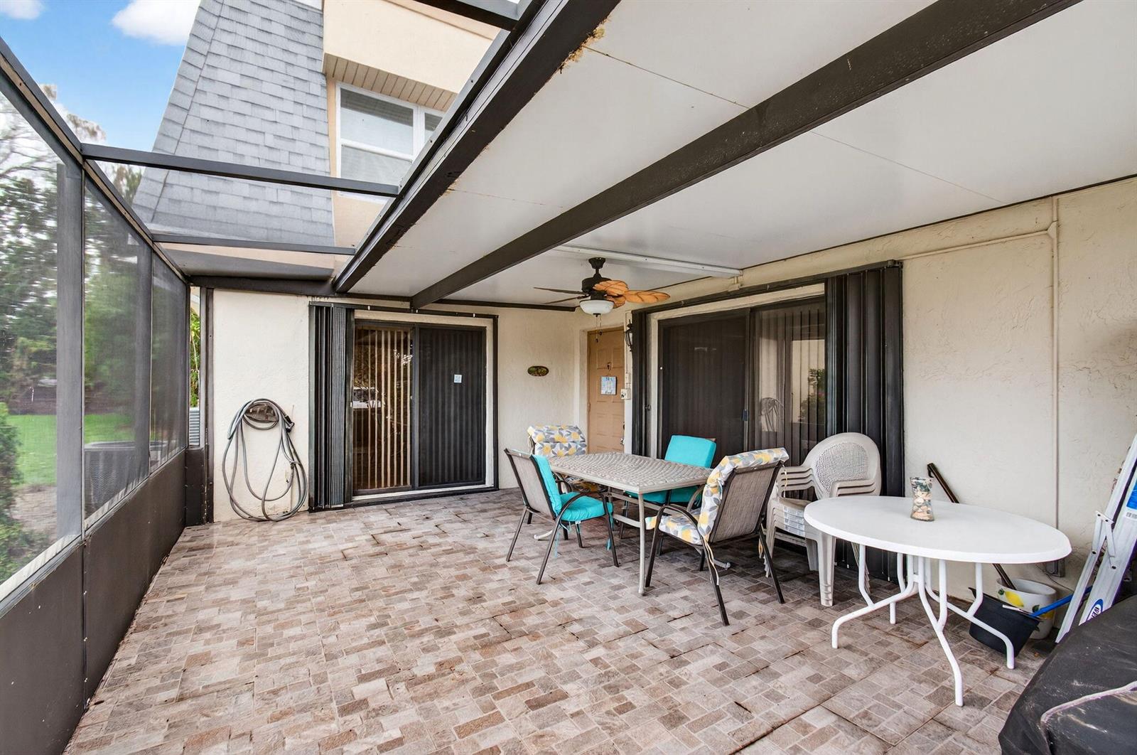 A screened-in patio features a tiled floor, a ceiling fan, and outdoor dining furniture — 2686 NW 7th Court # C, Delray Beach FL 33445, DELRAY BEACH, FL