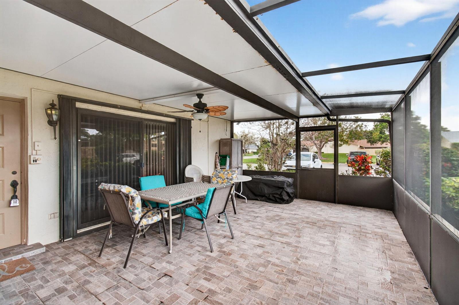 A screened-in patio features a tiled floor, a dining set, and a ceiling fan — 2686 NW 7th Court # C, Delray Beach FL 33445, DELRAY BEACH, FL
