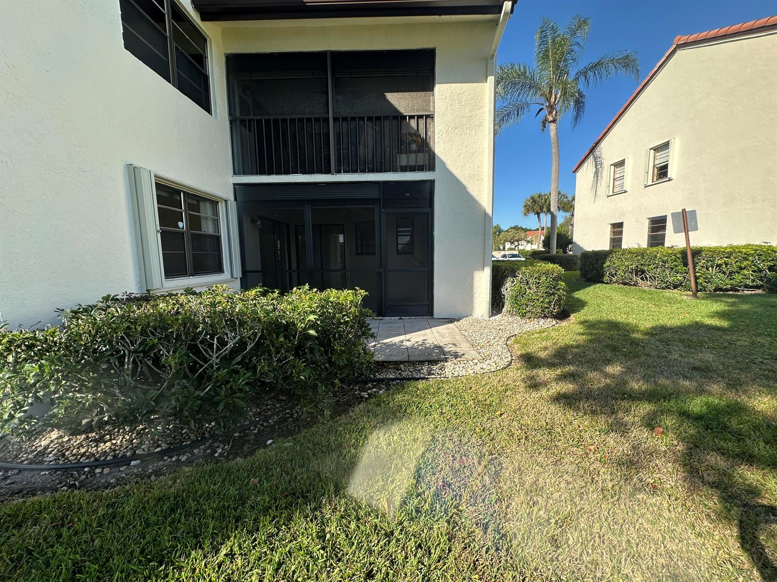 A two-story building features a screened-in patio on the ground floor and a balcony above — 5819 Parkwalk Drive, Boynton Beach FL 33472, BOYNTON BEACH, FL