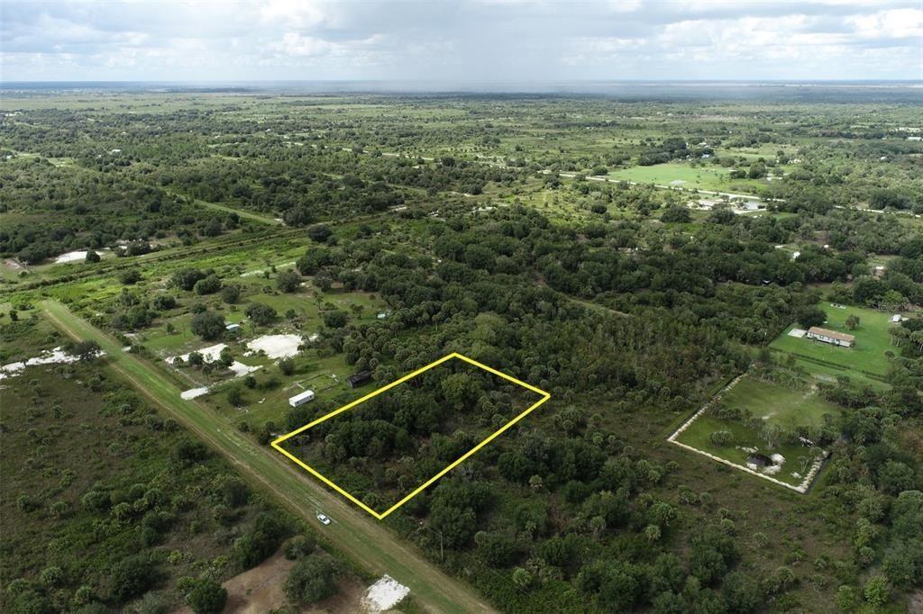 An aerial view shows a utility pole and power lines bordering a dense, wooded lot — 19731 NW 266th Street, Okeechobee FL 34972, OKEECHOBEE, FL