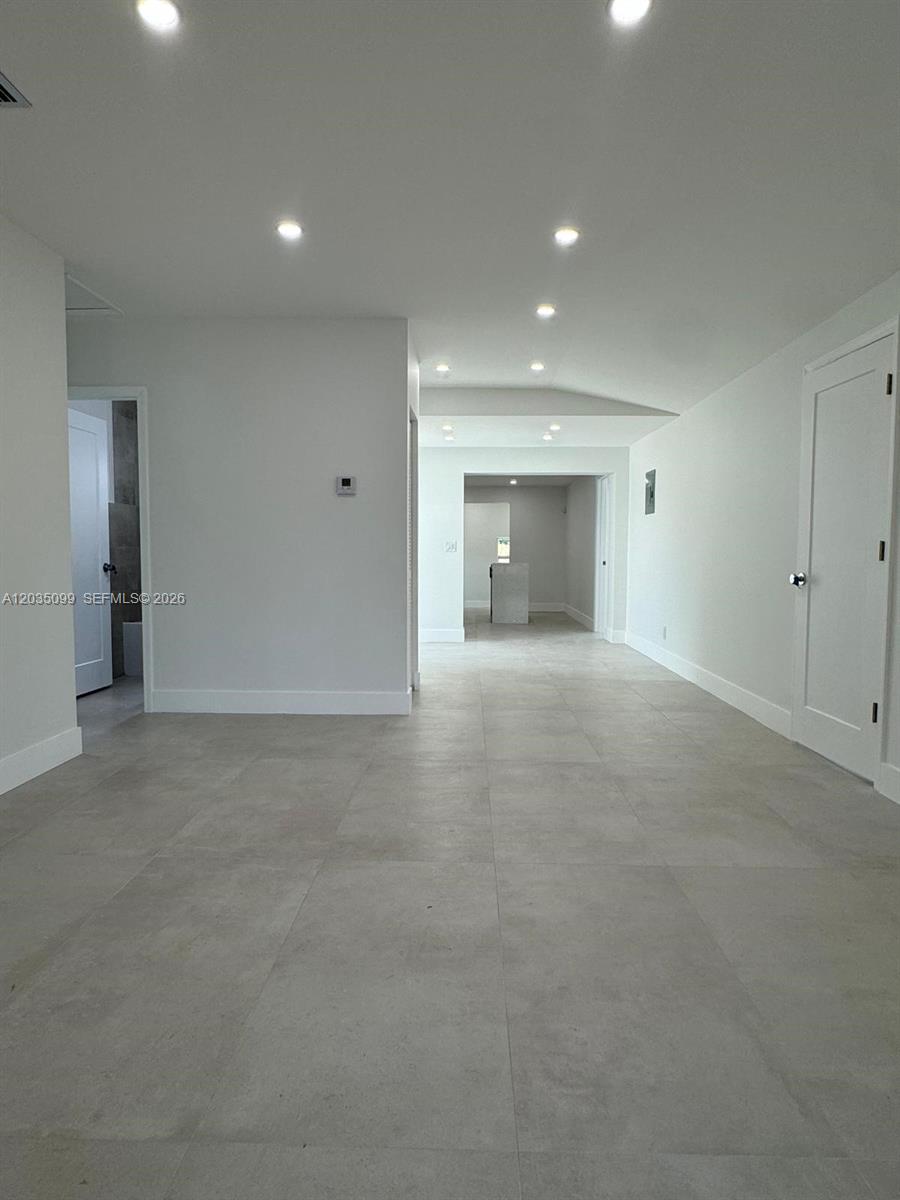 A bright, minimalist hallway features light gray tile flooring, recessed ceiling lights, and white walls — 4028 SW 49th Ct, Dania Beach FL 33314, DANIA BEACH, FL