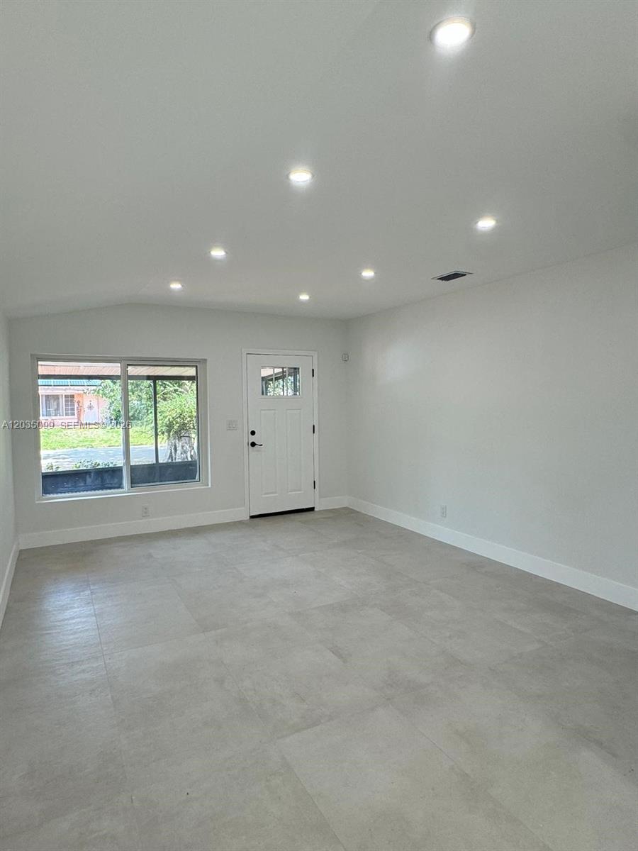 A bright, empty room features light gray tile flooring, white walls, and recessed ceiling lighting — 4028 SW 49th Ct, Dania Beach FL 33314, DANIA BEACH, FL