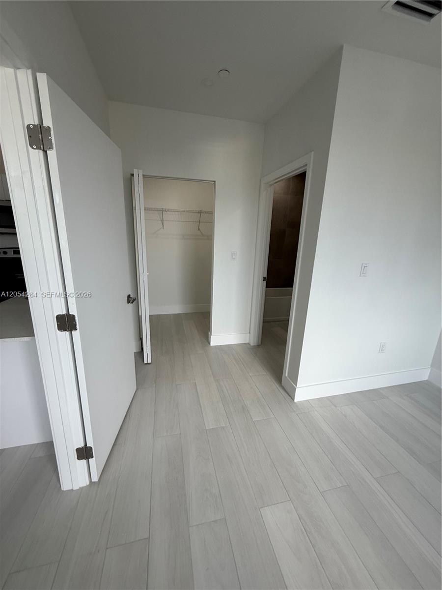 A room features light wood-look flooring, white walls, a walk-in closet, and an adjacent bathroom — 1091 E 17th St # 403, Hialeah FL 33010, HIALEAH, FL