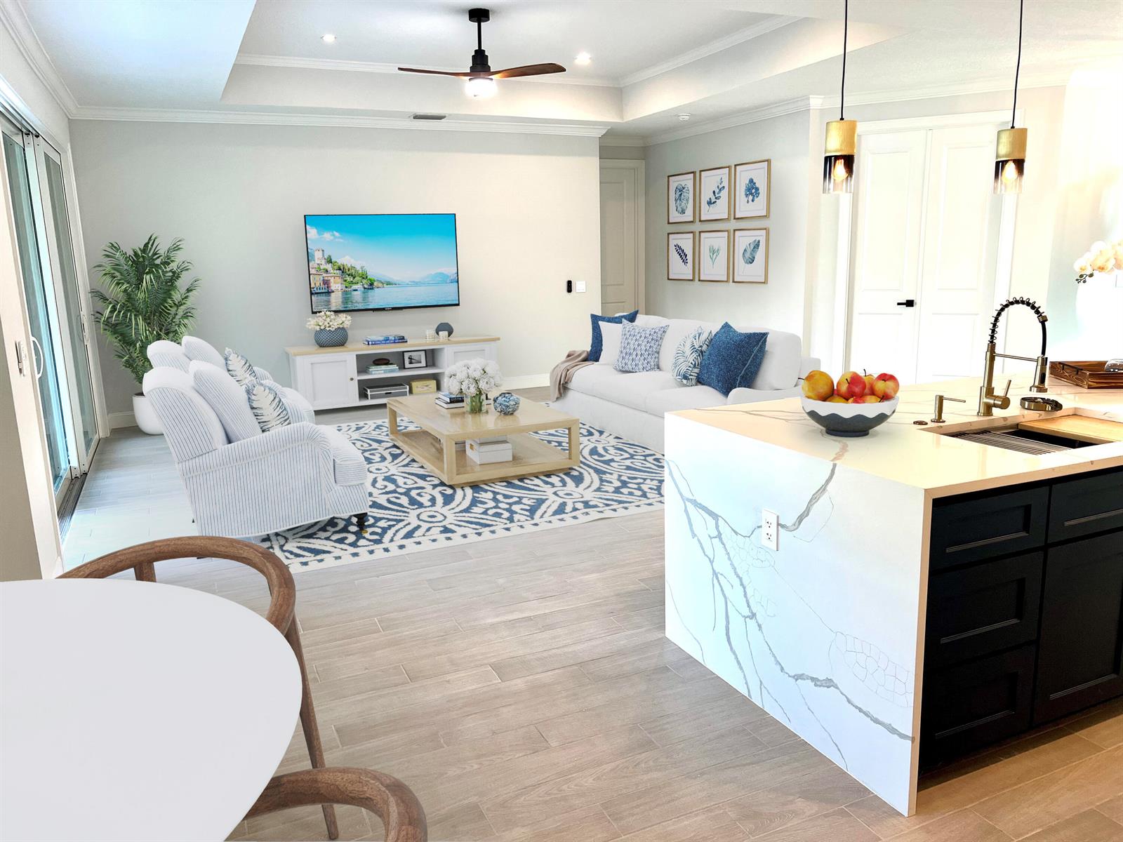 An open-concept living room and kitchen featuring a white marble island and blue-patterned area rug — 6660 49th, Vero Beach FL 32967, VERO BEACH, FL