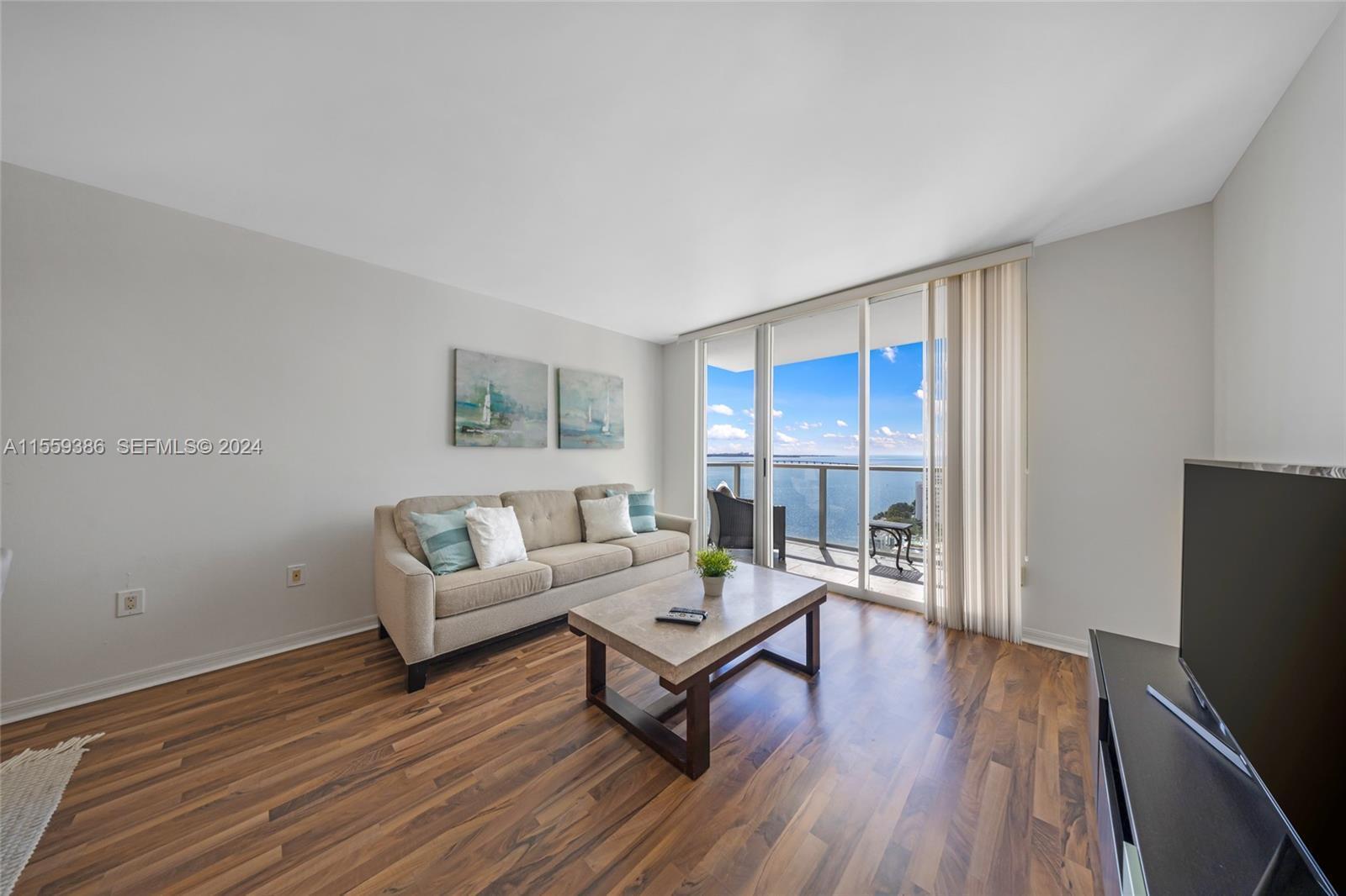 A living room features wood flooring, a beige sofa, a coffee table, and a balcony view — 1155 Brickell Bay Drive Apt 2207, Miami FL 33131, MIAMI, FL