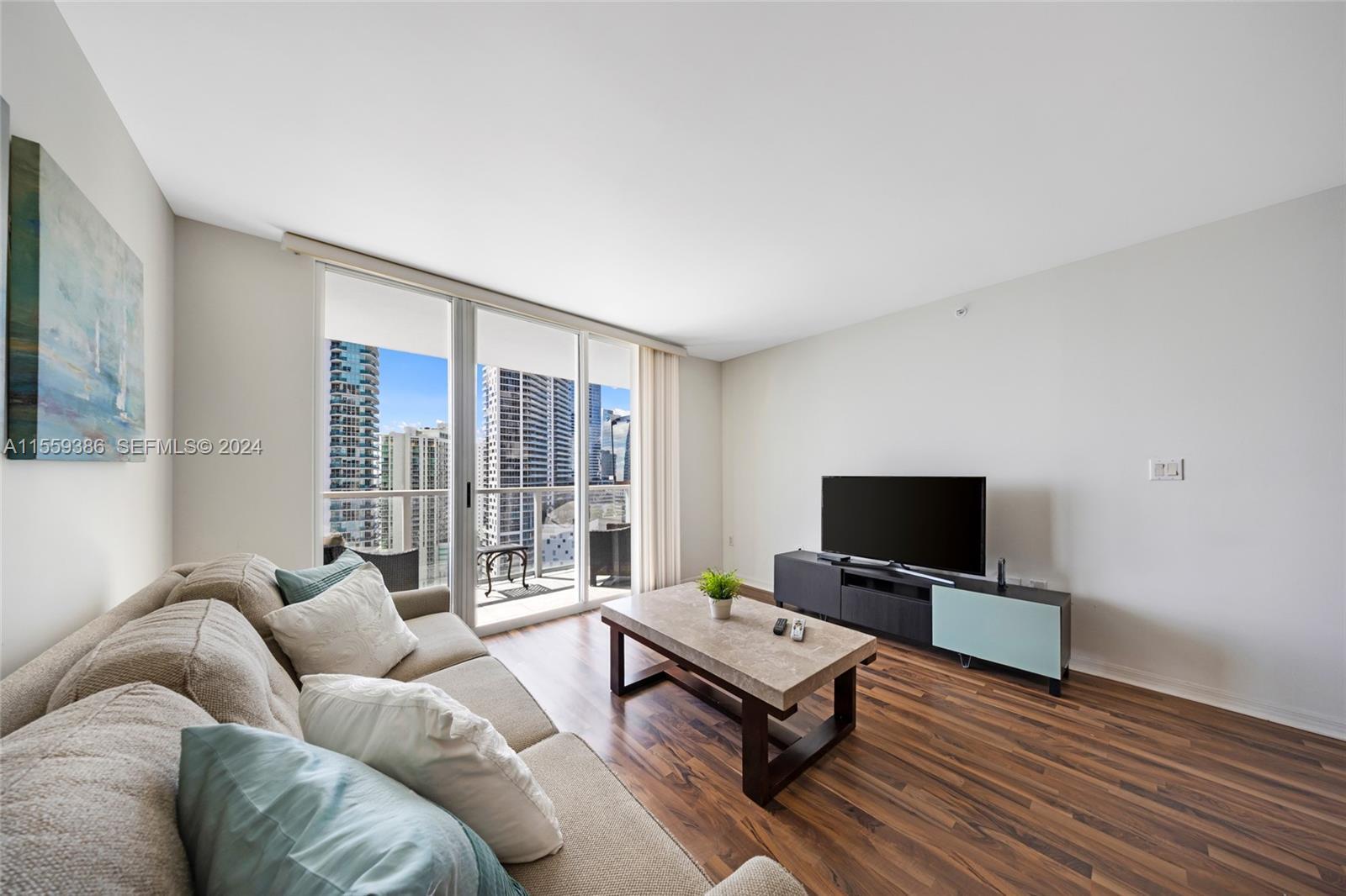 A living room features wood-look flooring, a beige sofa, a coffee table, and a balcony — 1155 Brickell Bay Drive Apt 2207, Miami FL 33131, MIAMI, FL