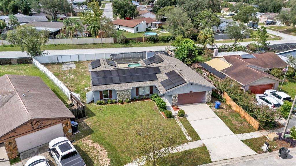 An aerial view shows a single-story house with solar panels and a screened-in pool area — 1306 BORDEN COURT, VALRICO, FL