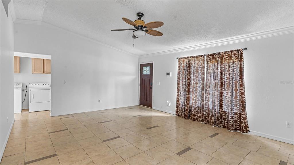 A living room with light tile flooring, a ceiling fan, and a brown front door — 1306 BORDEN COURT, VALRICO, FL