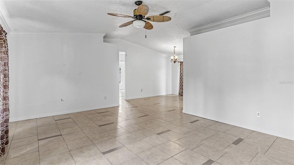 An empty living area features light-colored tile flooring, white walls, and a ceiling fan — 1306 BORDEN COURT, VALRICO, FL