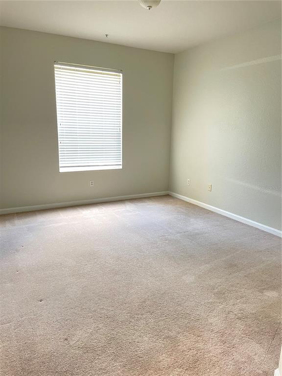 An empty bedroom features beige walls, tan carpet, and a window with white blinds — 3314 ROBERT TRENT JONES DRIVE UNIT 10901, ORLANDO, FL