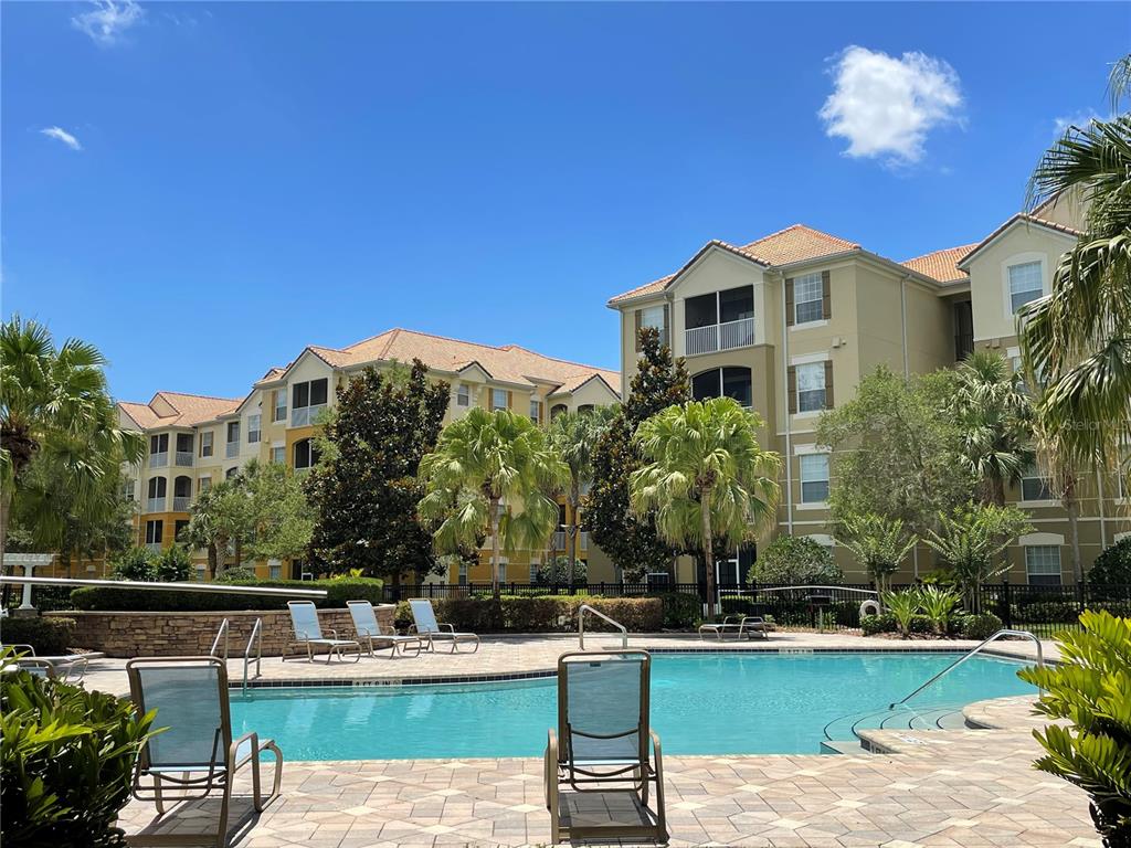 A swimming pool with lounge chairs sits in front of a multi-story apartment building — 3314 ROBERT TRENT JONES DRIVE UNIT 10901, ORLANDO, FL