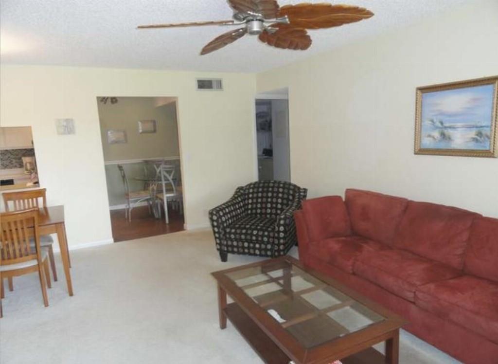 A living room features a red sofa, a patterned armchair, a coffee table, and ceiling fan — 814 Sky Pine Way # 2, FL 33415, FL