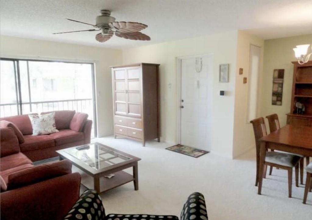 A living room with a red sofa, glass coffee table, ceiling fan, and dining area — 814 Sky Pine Way # 2, FL 33415, FL