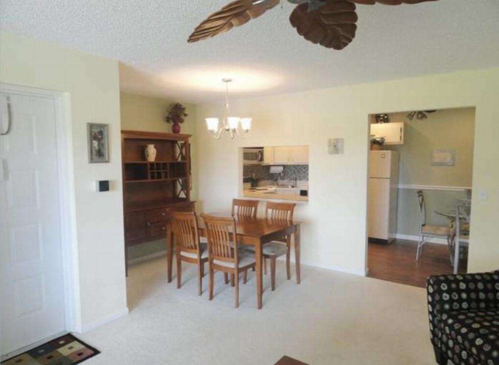A dining area with a wooden table and hutch sits adjacent to a kitchen pass-through window — 814 Sky Pine Way # 2, FL 33415, FL