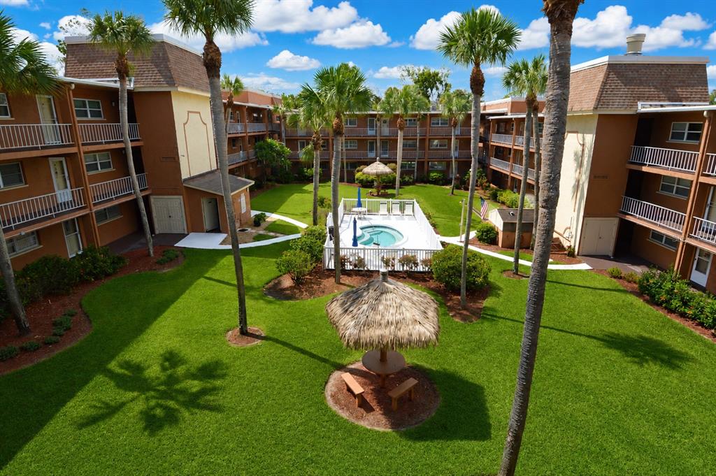 An aerial view of an apartment complex courtyard featuring a pool, palm trees, and gazebo — 12760 INDIAN ROCKS ROAD UNIT 570, LARGO, FL
