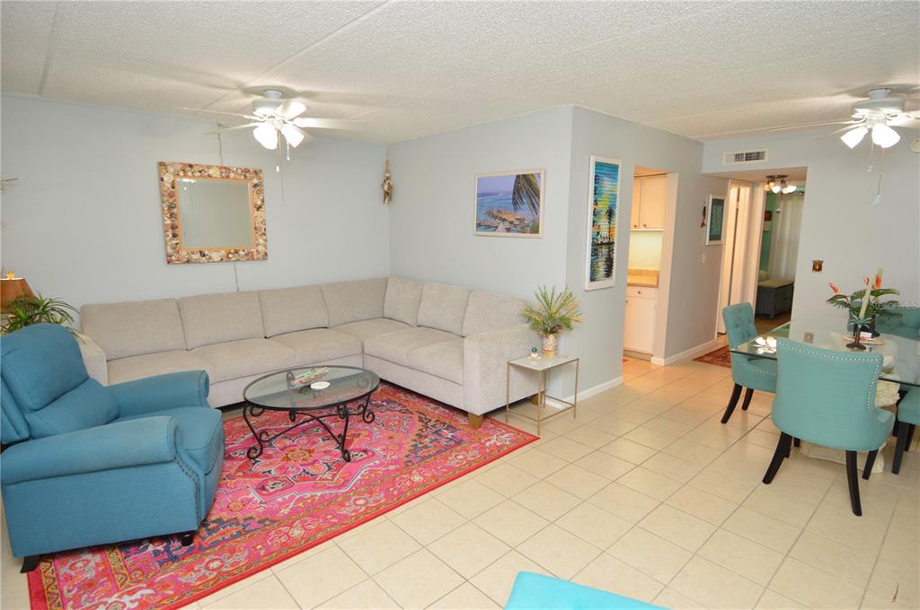 A living room features a sectional sofa, a blue armchair, and a pink patterned rug — 12760 INDIAN ROCKS ROAD UNIT 570, LARGO, FL