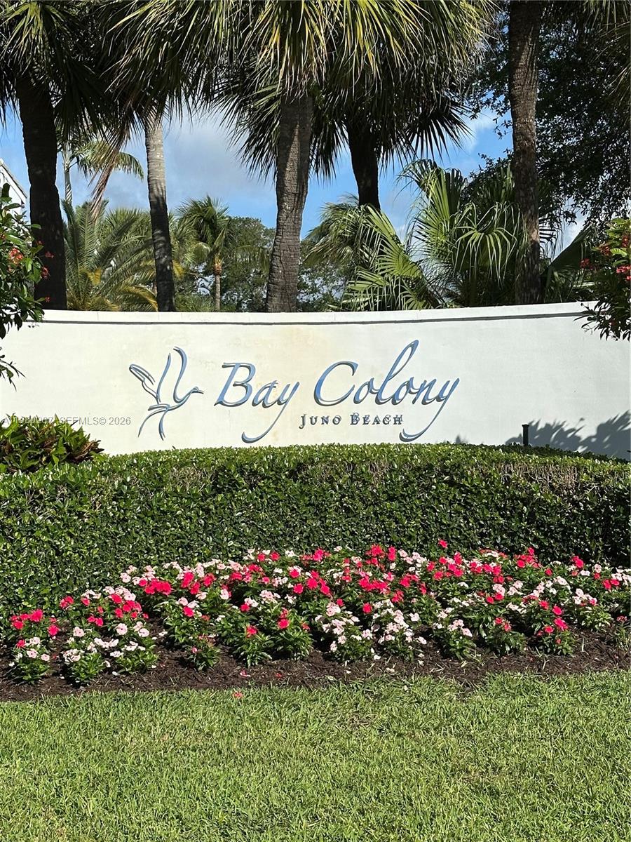 A white curved monument sign for Bay Colony in Juno Beach sits behind flowering bushes — 915 S Bay Colony Dr S, Juno Beach FL 33408, JUNO BEACH, FL