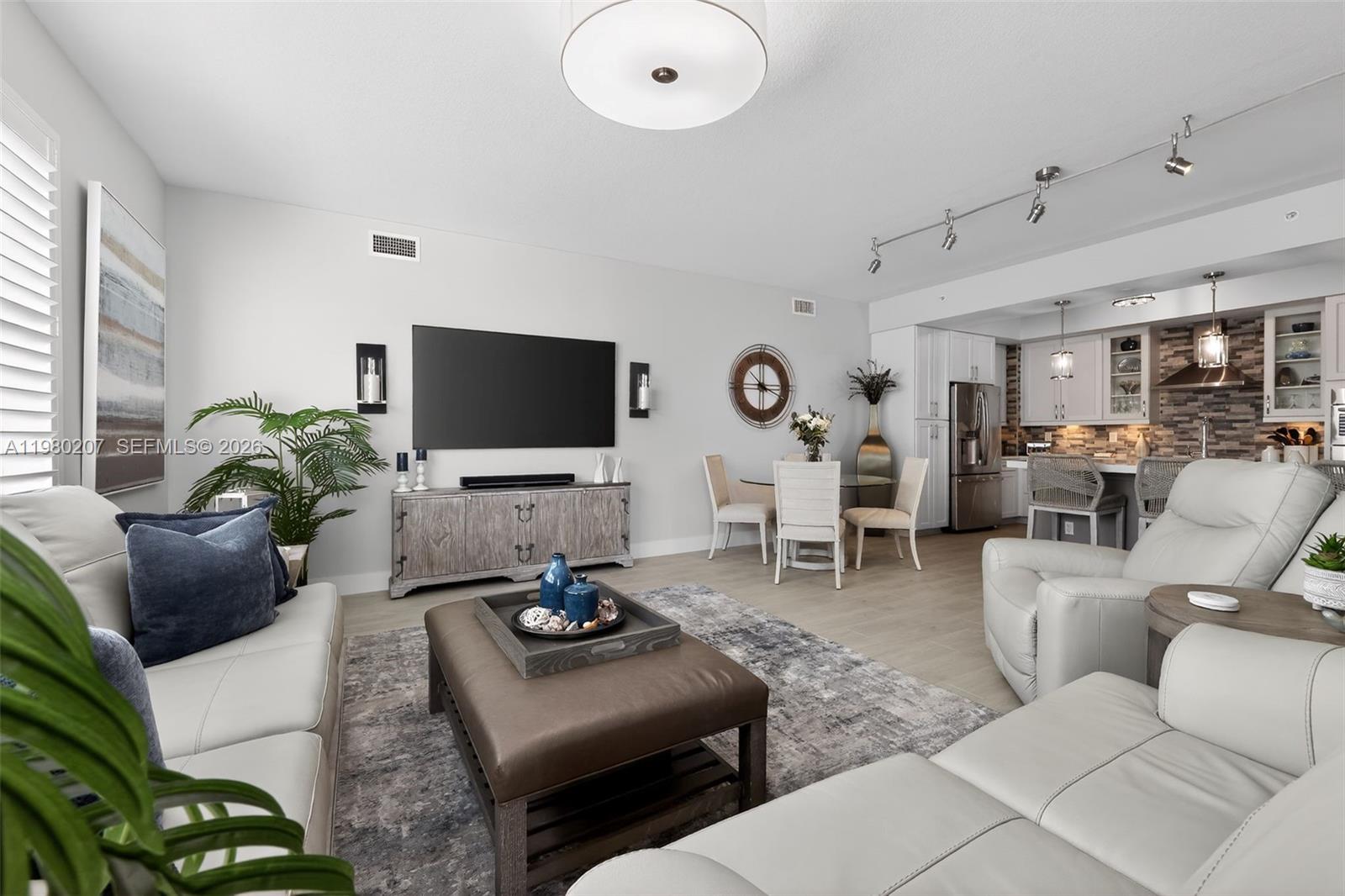 A living room features light gray walls, white leather furniture, and an open-concept kitchen — 915 S Bay Colony Dr S, Juno Beach FL 33408, JUNO BEACH, FL