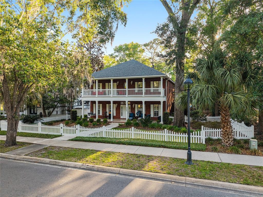 A two-story brick house features a white double-decker porch and a white picket fence — 240 SW 131ST STREET, NEWBERRY, FL