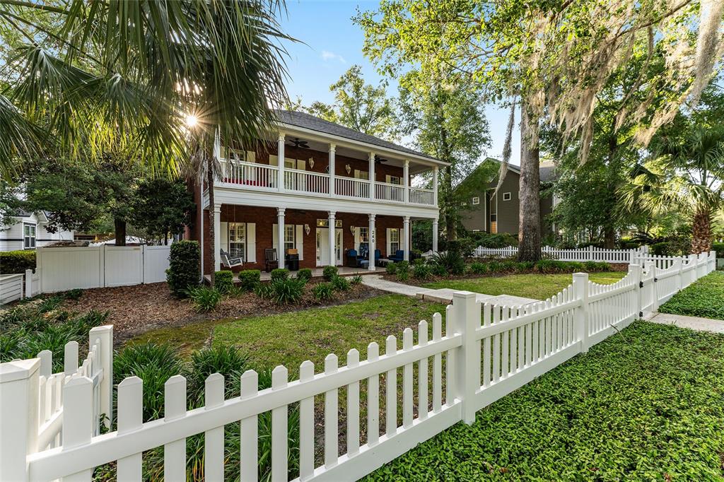 A two-story brick house with a double-decker porch sits behind a white picket fence — 240 SW 131ST STREET, NEWBERRY, FL