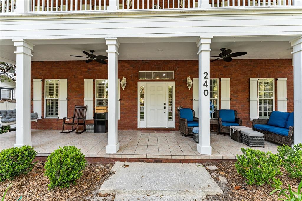 A brick-front porch features white columns, tiled flooring, outdoor furniture, and a white front door — 240 SW 131ST STREET, NEWBERRY, FL