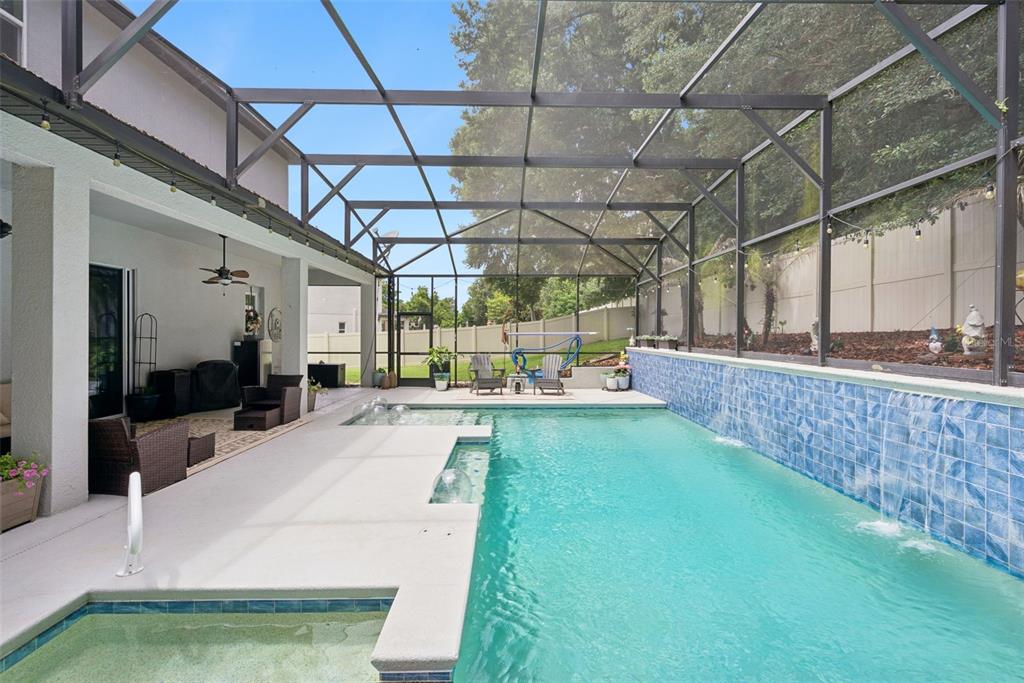 A screened-in patio features a swimming pool with a tiled water feature and a spa — 3113 PINENUT DRIVE, APOPKA, FL