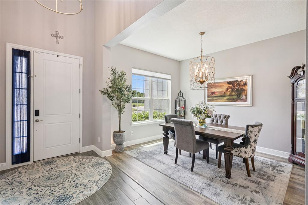 A dining area with a wooden table, upholstered chairs, and a chandelier near an entryway — 3113 PINENUT DRIVE, APOPKA, FL